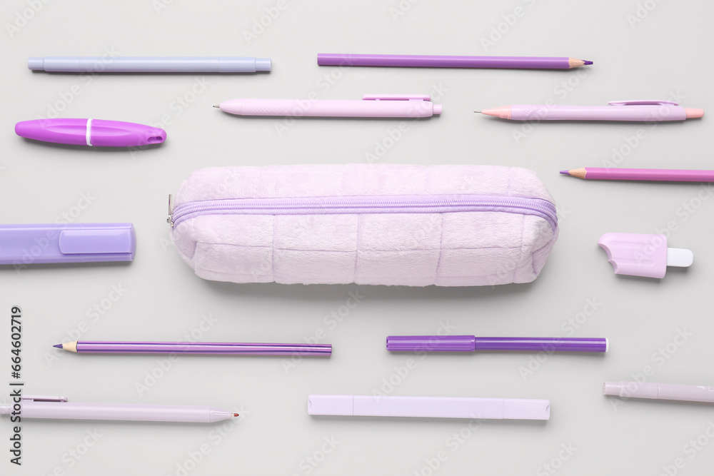 Purple pencil case with school stationery on grey background