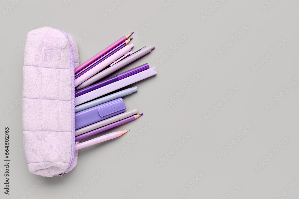 Purple pencil case with school stationery on grey background