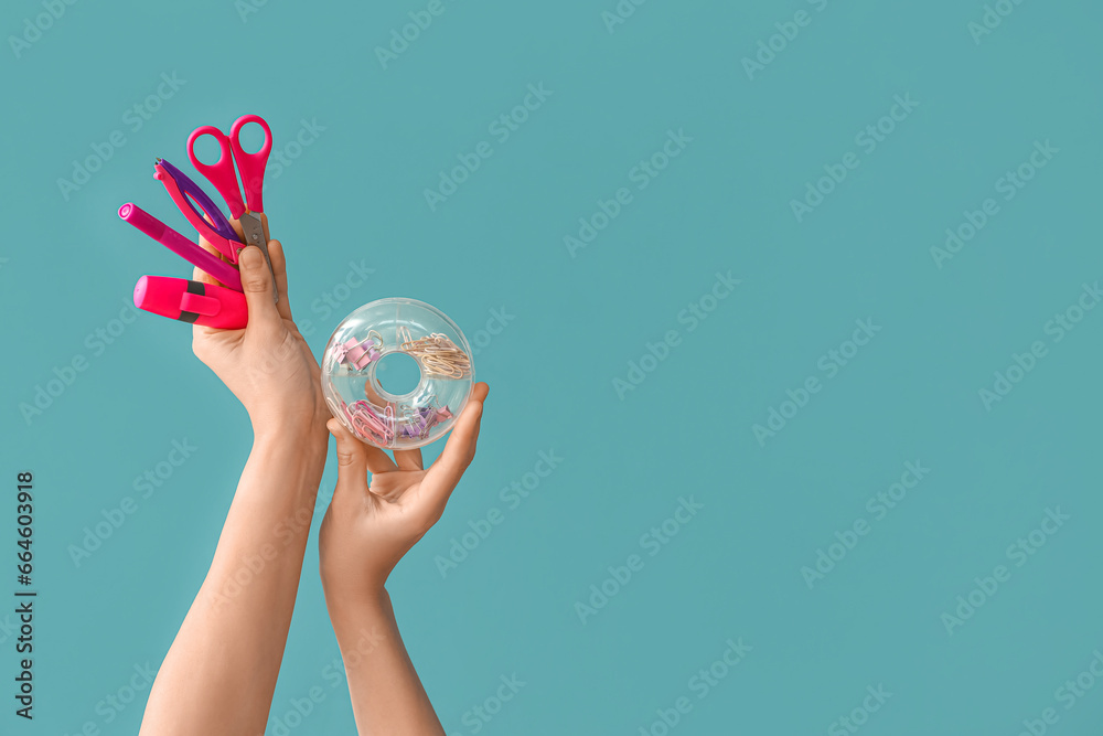 Female hands holding school supplies on blue background