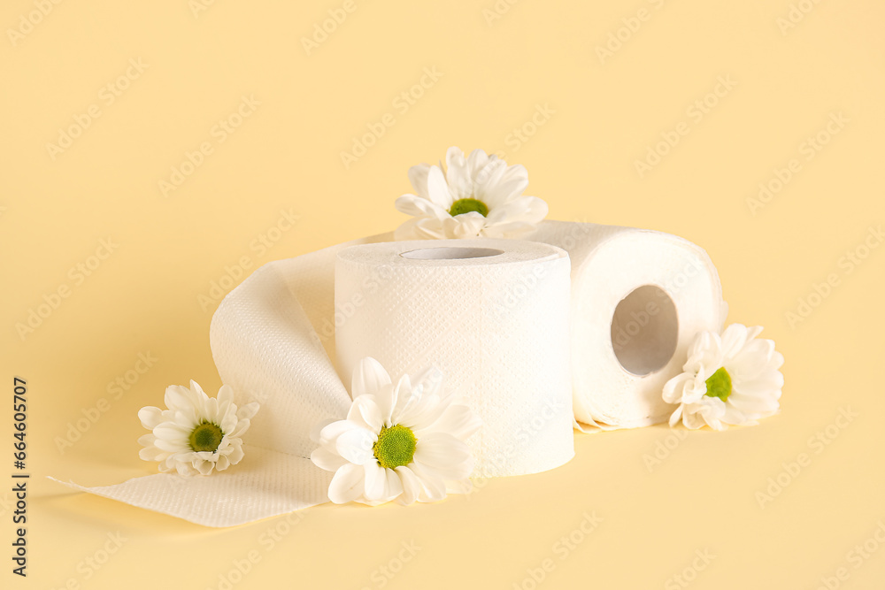 Composition with rolls of toilet paper and chamomile flowers on color background