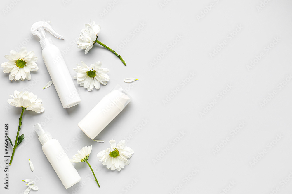 Composition with cosmetic products and chamomile flowers on grey background