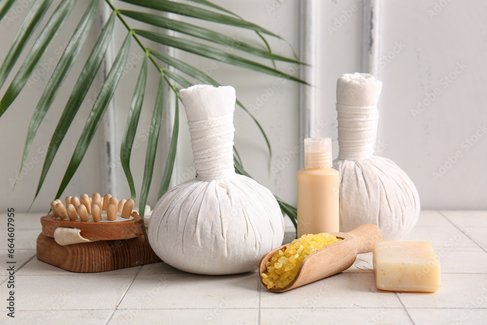 Set of spa accessories, cosmetics and palm leaf on light background