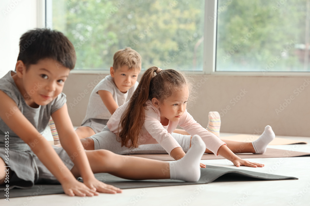 Group of little children practicing yoga in gym