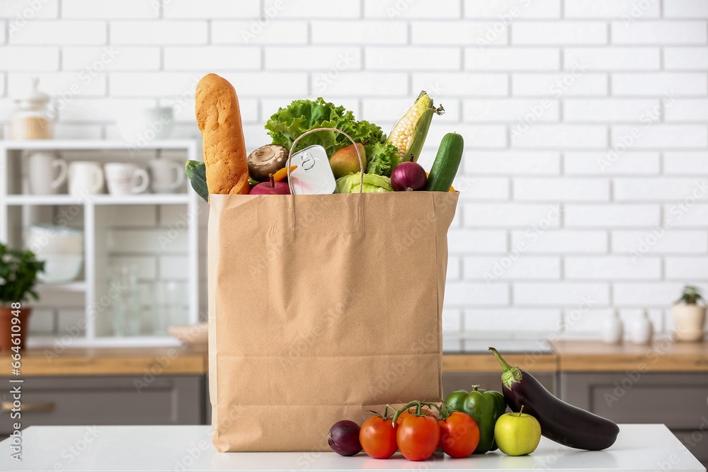 Shopping paper bag with fresh products on table in kitchen