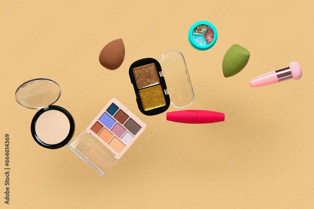 Flying decorative cosmetics on pale orange background