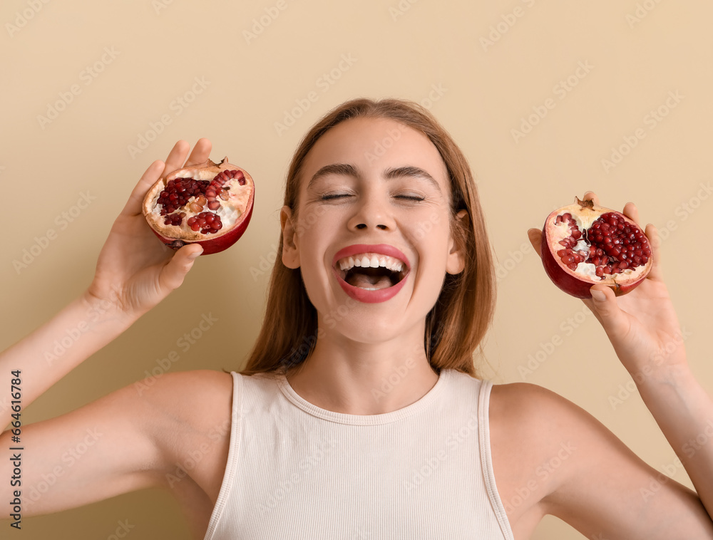 Happy young woman with pomegranate on beige background, closeup