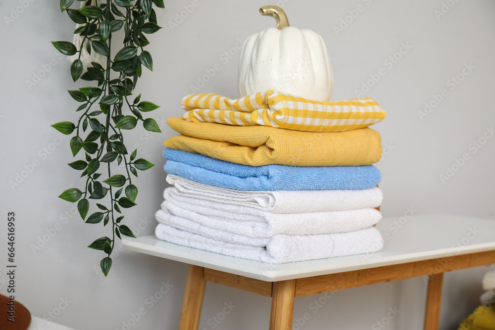 Stack of clean towels and decor on table near light wall