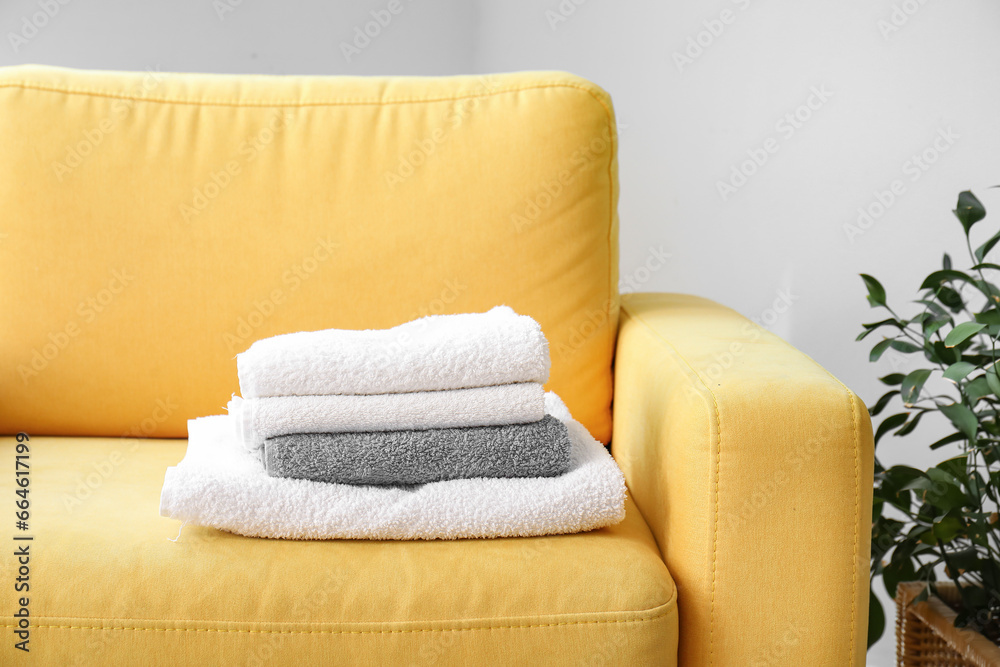 Stack of clean towels on colorful armchair in room, closeup