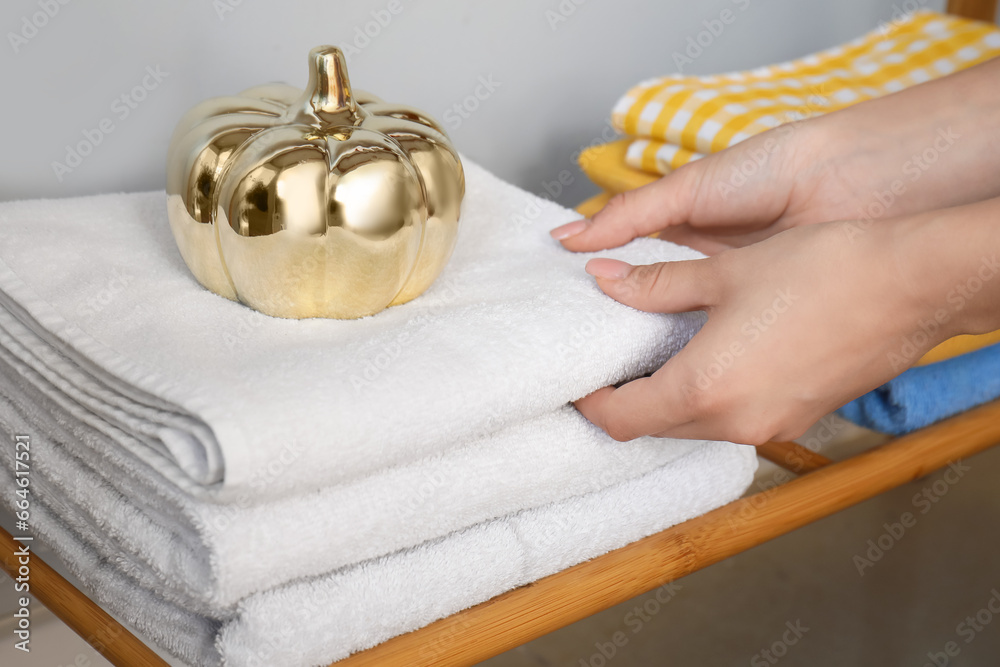 Woman stacking clean towels on shelf, closeup