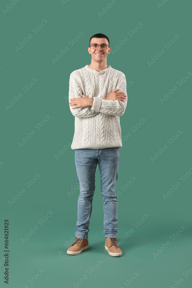 Young man in knitted sweater on green background