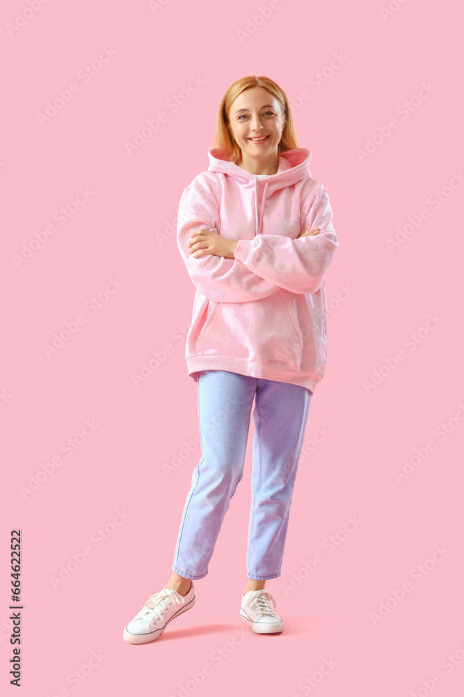 Mature woman in hoodie on pink background