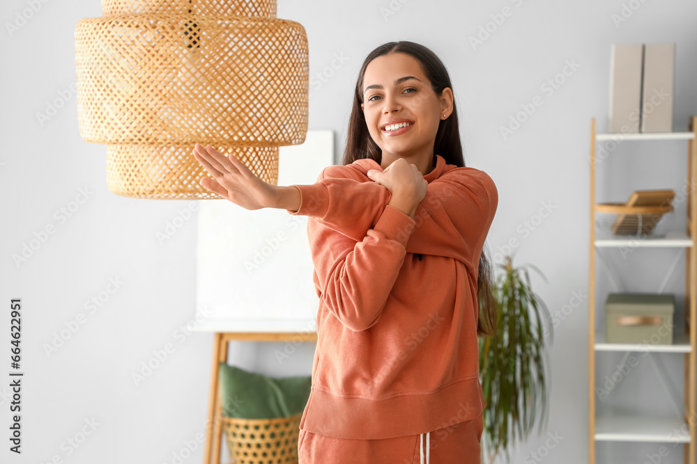 Sporty young woman in hoodie training at home