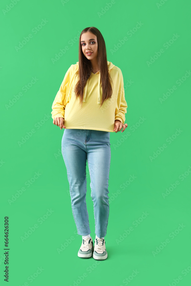 Young woman in hoodie on green background