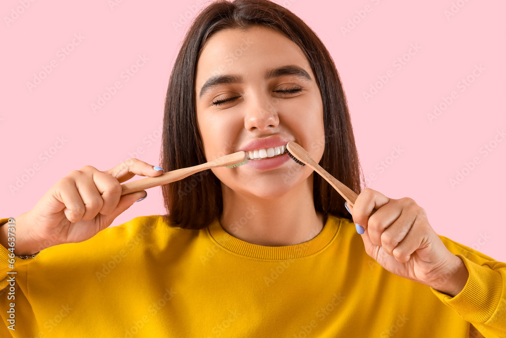 Smiling young woman with toothbrushes on pink background, closeup