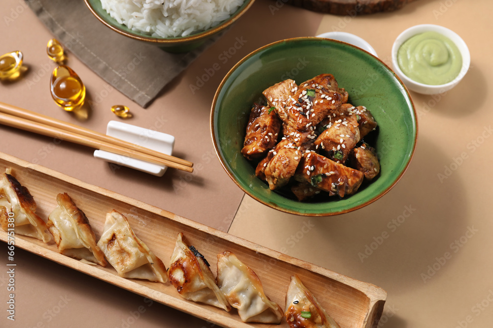 Tasty Chinese dishes and chopsticks on color background