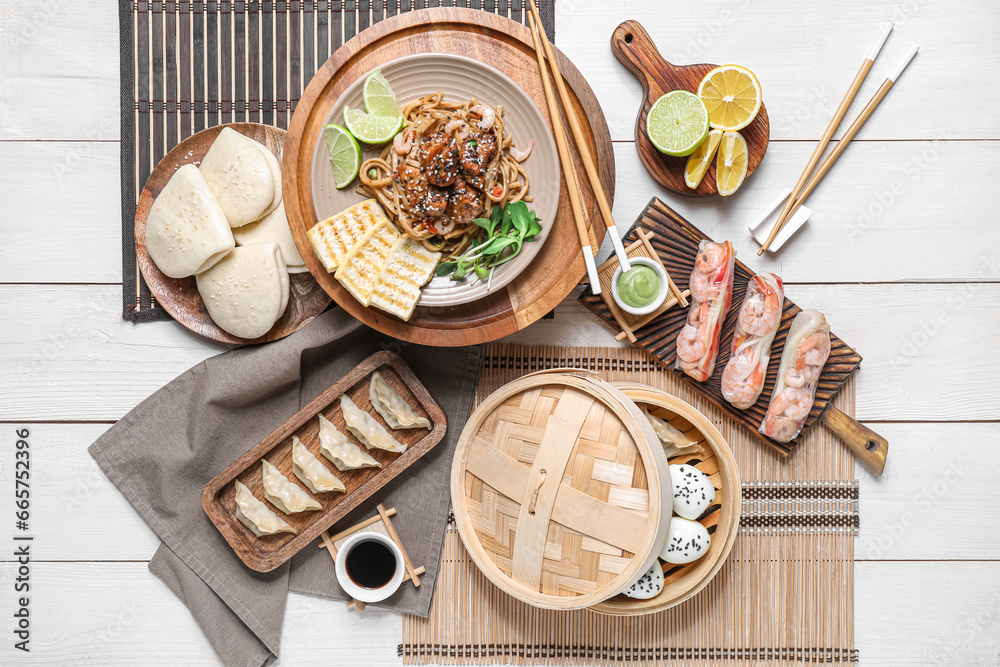 Composition with different Chinese dishes and chopsticks on light wooden background