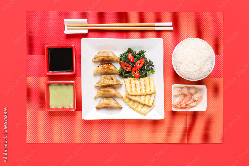 Composition with different Chinese dishes and chopsticks on red background