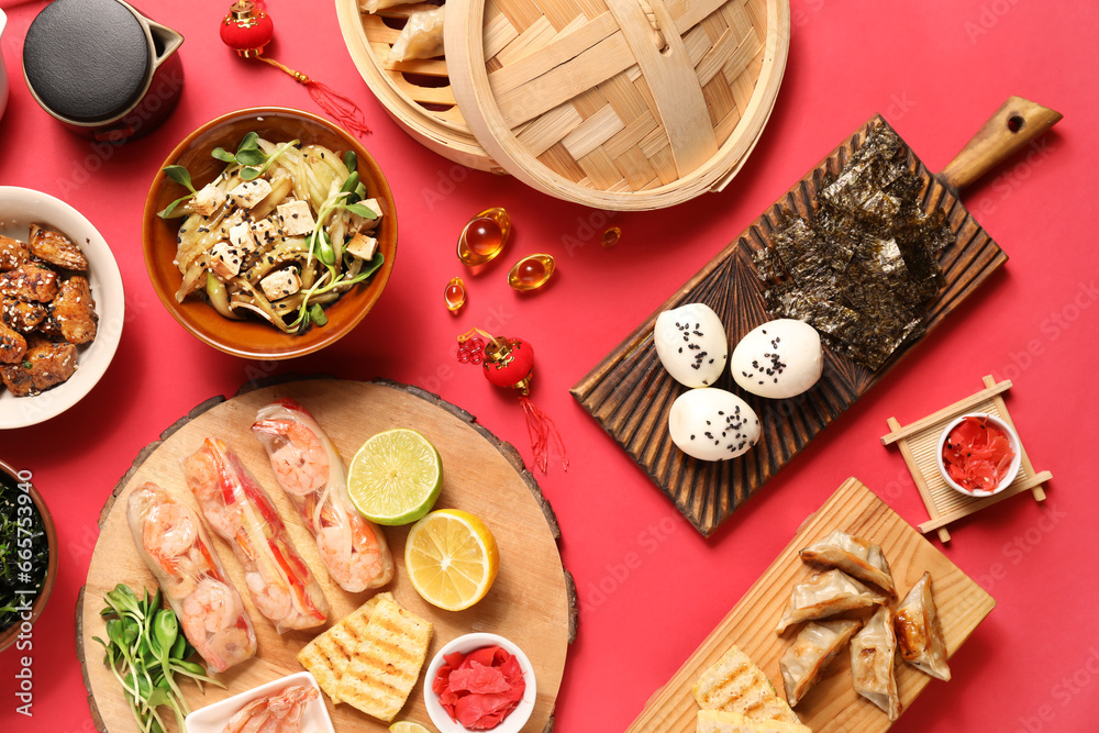 Composition with delicious Chinese dishes and decor on red background