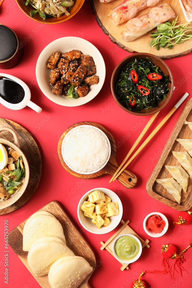 Composition with delicious Chinese dishes on red background