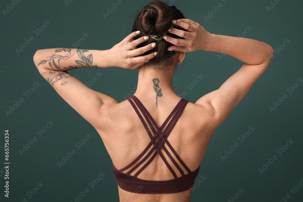 Tattooed young woman on green background, back view