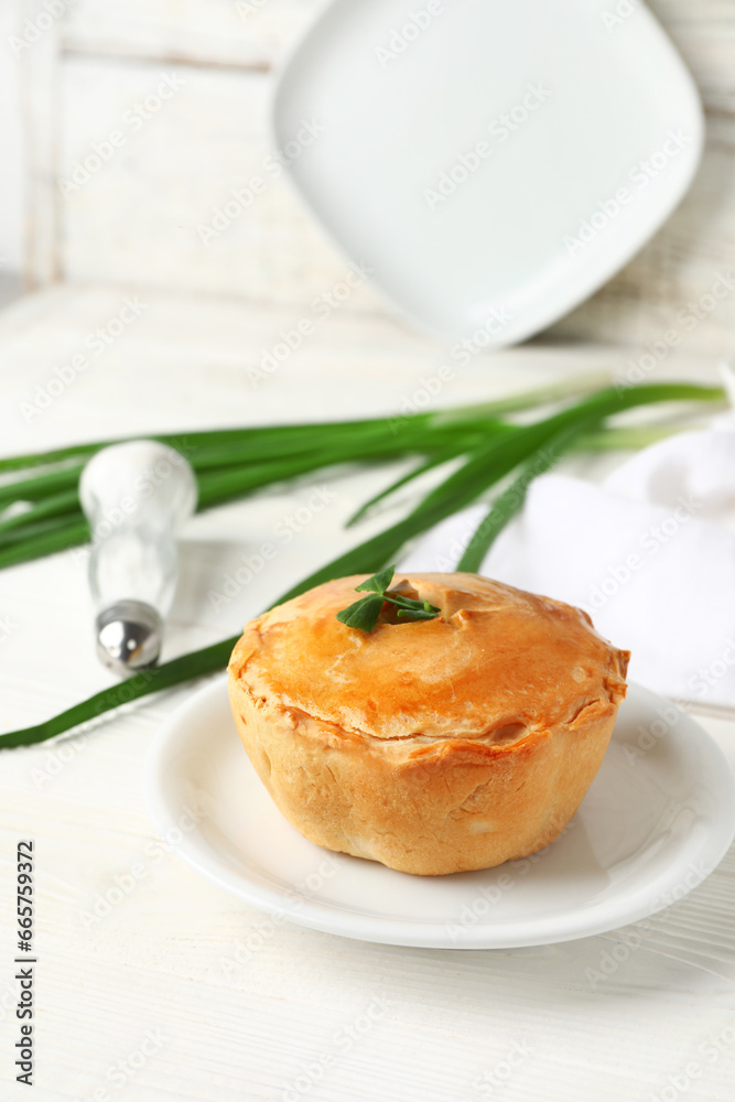 Plate with tasty meat pot pie on light wooden background