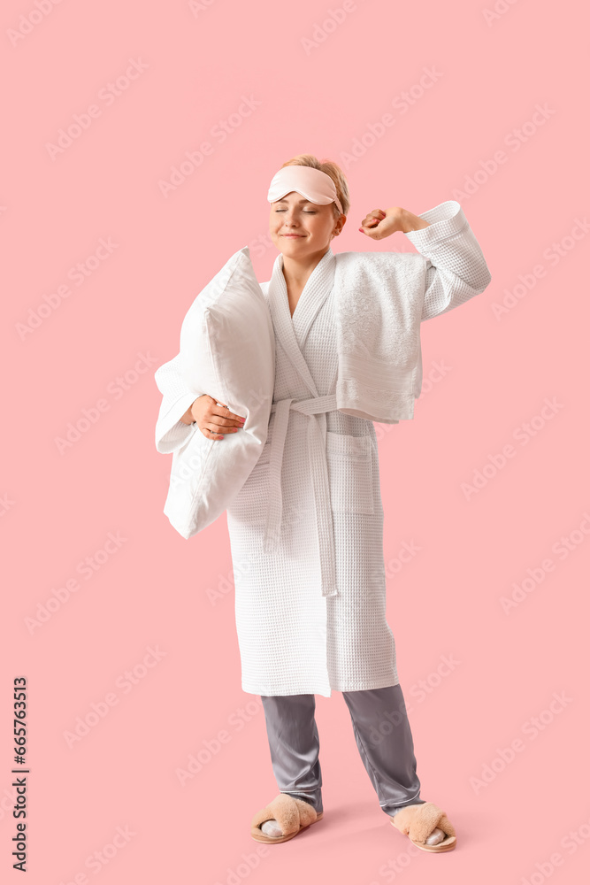 Young woman in sleeping mask with pillow on pink background