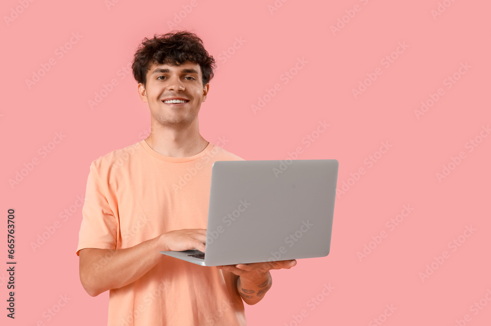 Male programmer working with computer on pink background