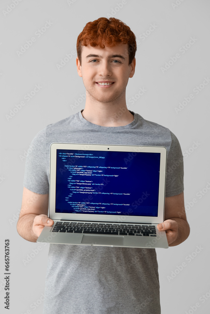 Male programmer with laptop on light background