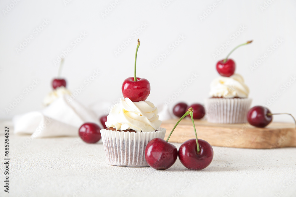 Tasty cherry cupcake on light background