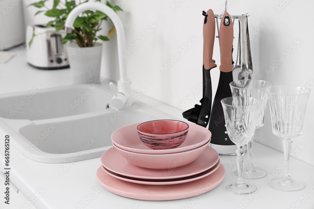 Set of clean pink dishes on counter in kitchen, closeup