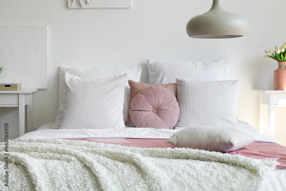 Cozy bed with white blanket and pillows in bedroom