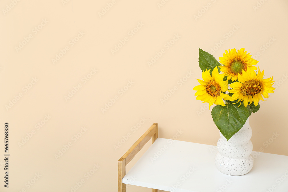 Vase with sunflowers on shelf near beige wall