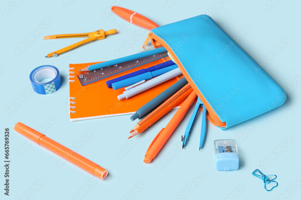 Stylish pencil case with different school stationery on blue background, closeup