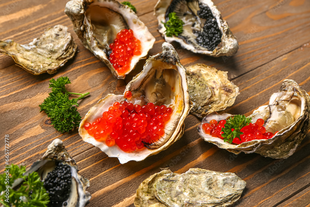 Tasty oysters with black and red caviar on wooden background