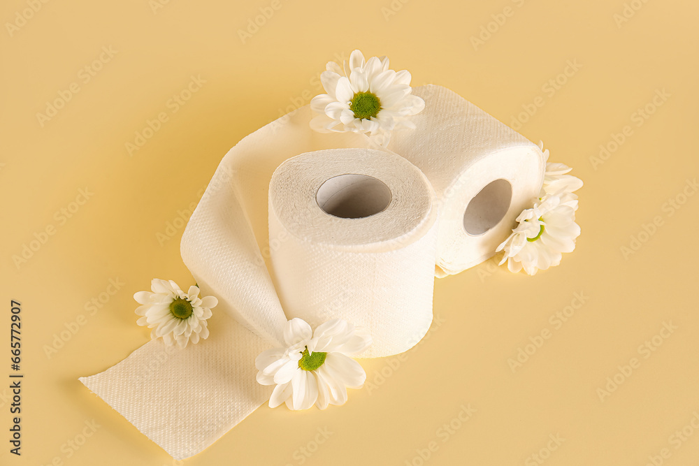 Composition with rolls of toilet paper and chamomile flowers on color background