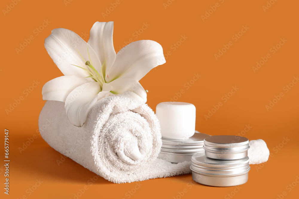 Set of cosmetic products, clean towel and lily flower on color background