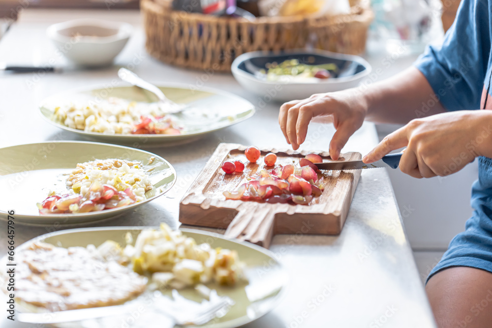 A woman cuts grapes on a cutting board.