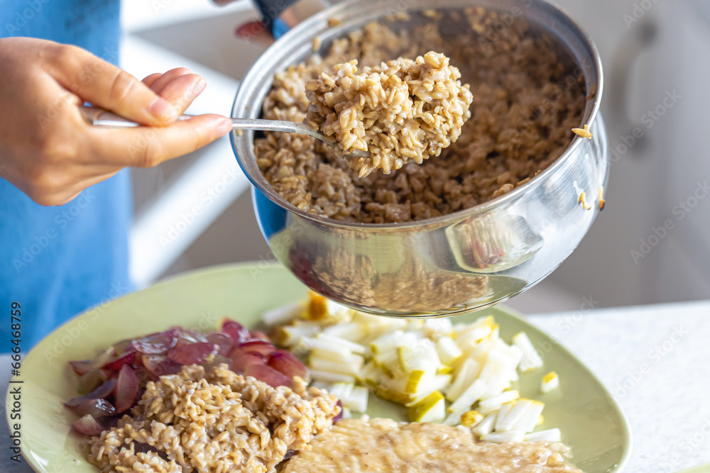 A woman prepares oatmeal with fruits, close-up.