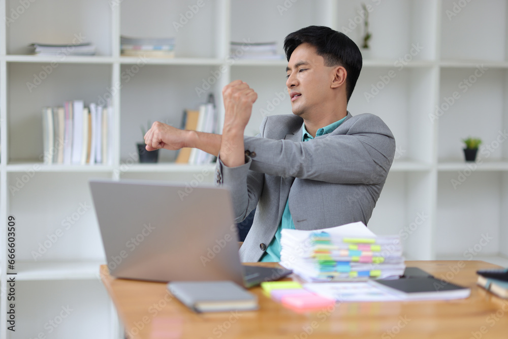 A aches businessman stretching to relax after working in the office.