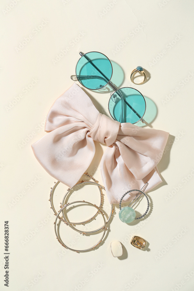 Stylish jewelry with sunglasses on light background