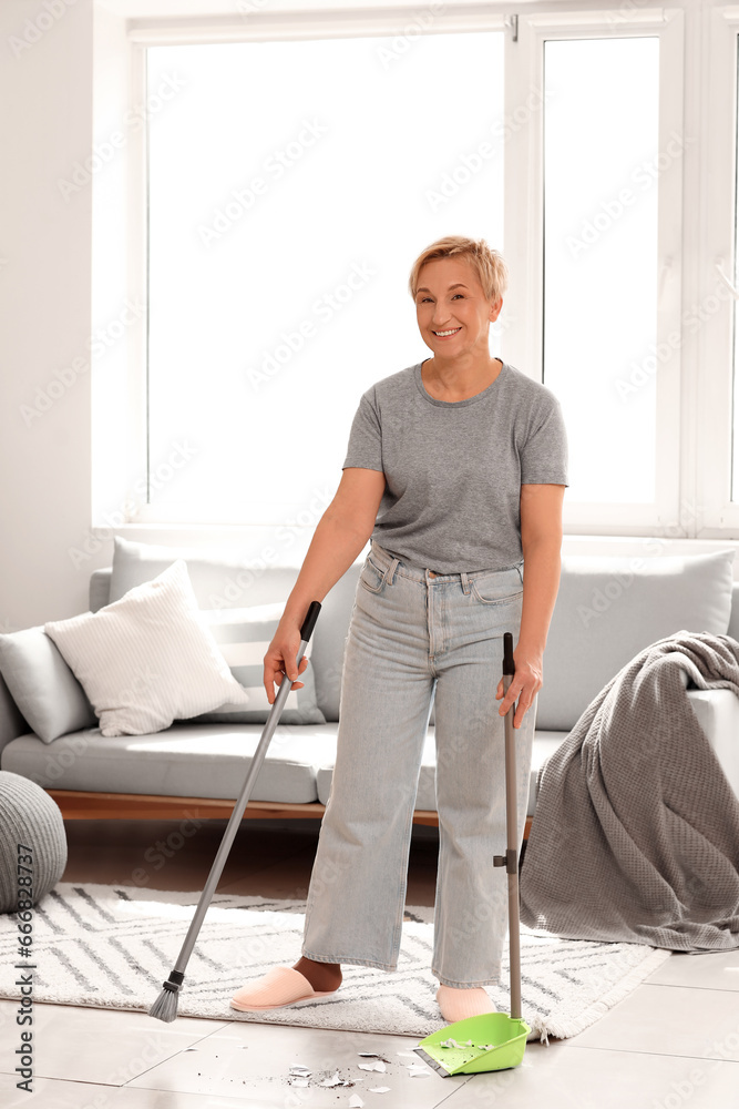 Mature woman sweeping floor in room