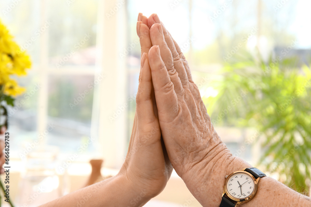 Senior woman with her granddaughter touching hands at home, closeup