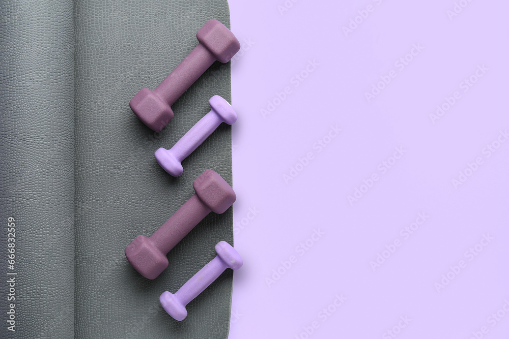 Set of dumbbells and yoga mat on lilac background