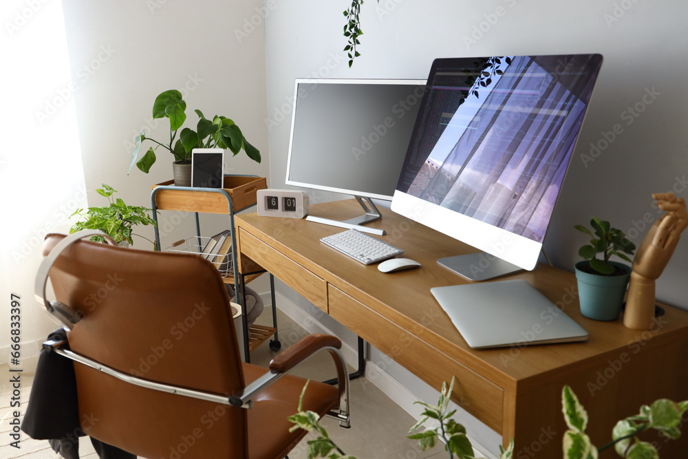 Programmers workplace with computer monitors in light office