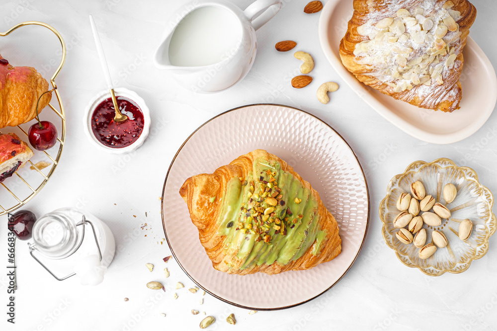 Composition with tasty croissants, pistachio nuts, jam and milk on light background