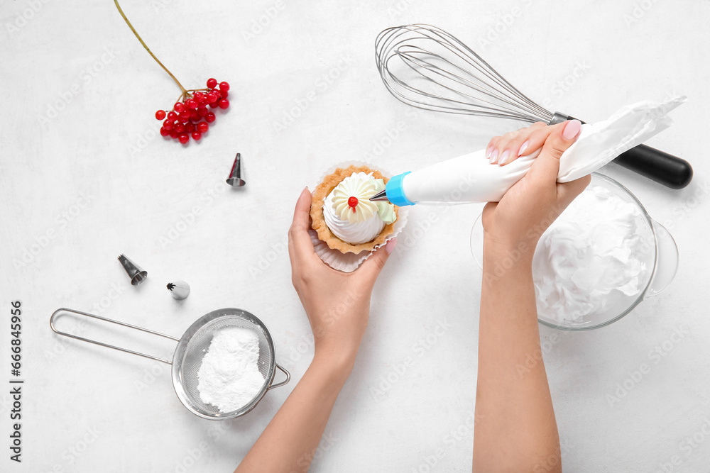 Female confectioner decorating tasty cake on white background