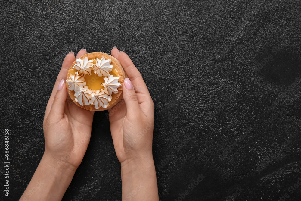 Female confectioner with tasty cake on black background