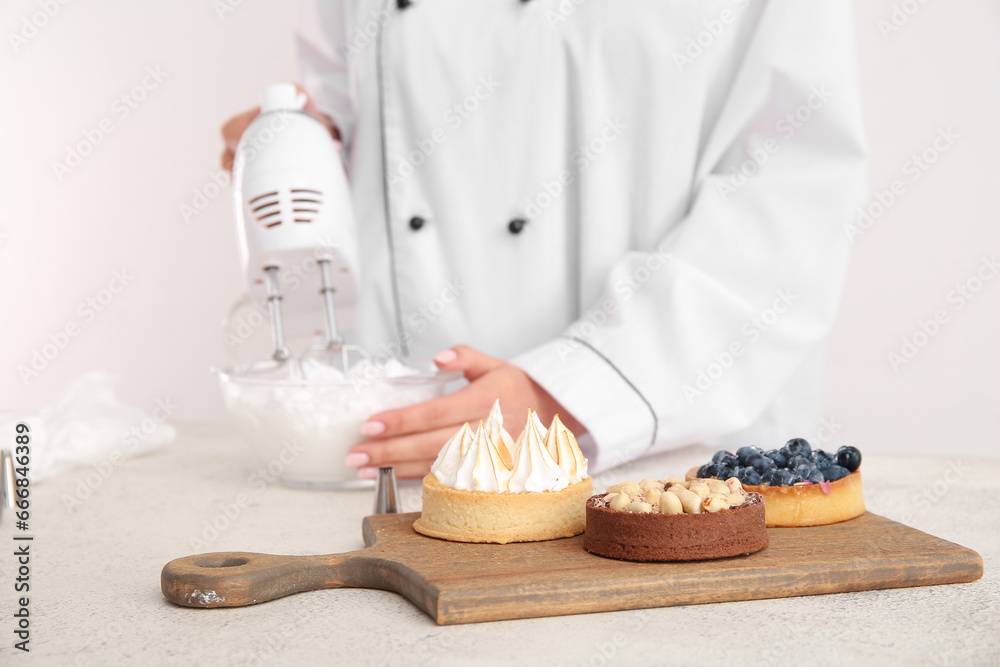 Wooden board of tasty cakes on white background