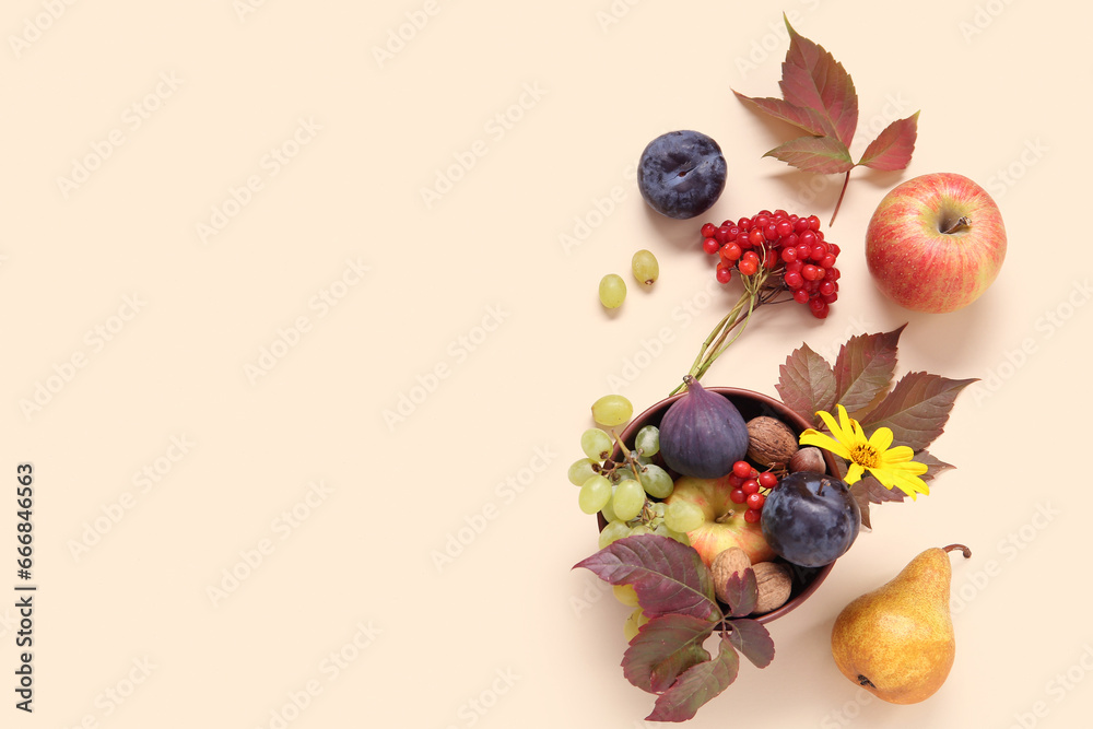 Bowl with different fresh fruits on beige background