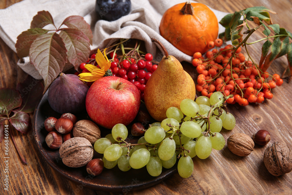 Plate with different fresh fruits and berries on wooden background